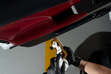 Car detailer cleans the auto door with brush and detergent. Process of removing dust and dirt from...
