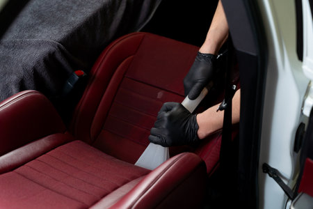 Hoovering car backseat with vacuum extractor. Detailing auto seats with special hoover nozzleの写真素材