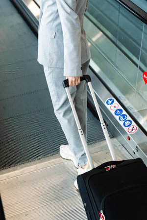 Woman is walking with blue travel suitcase with clothes for trip. Journey and vacation concept. Traveler suitcase in airport lobby close-upの写真素材