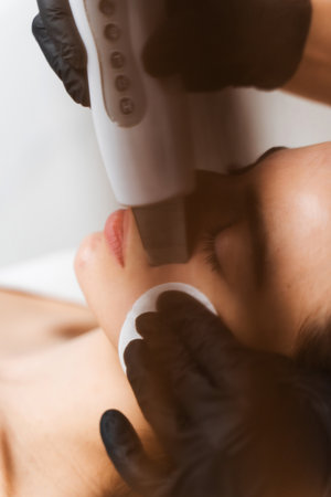 Cleansing facial skin with help of ultrasound cosmetology device. Process of applying cavitation...