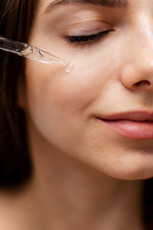 Attractive girl uses hyaluronic acid to restore her skin condition at home. Skin healing process with pipette hyaluronic acidの写真素材