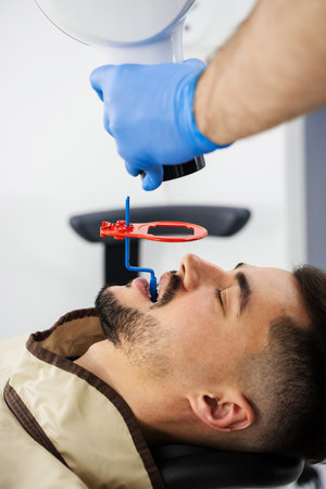 Doctor examining condition of teeth with stomatology x-ray hardware. Targeted x-ray scanning of teeth by a dentistの写真素材