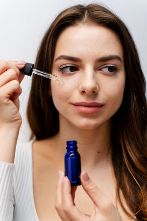 Attractive girl uses hyaluronic acid to restore her skin condition at home. Skin healing process with pipette hyaluronic acidの写真素材