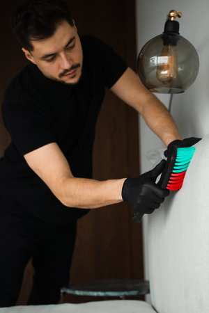 Cleaner is using brush to clean the sofa pillows. Dry cleaning service. Removing dust and stains...