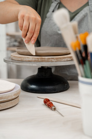 Crafting smooth angle conversion and textured ribs with a clay pottery scrapper. Girl is using a...