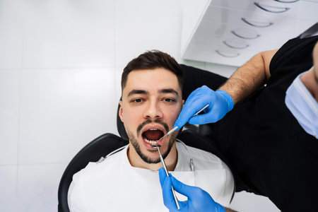 Preventative dental checkup close-up. Dentist uses dental explorer and mirror to advise the patient