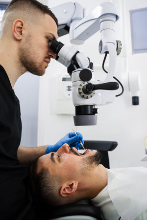 Dentist uses operating microscope to polish teeth of the patient. Operating dental digital microscope working processの写真素材