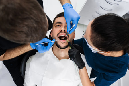 Initial examination of the patients oral cavity by a dentist. Handsome man is having preventive...