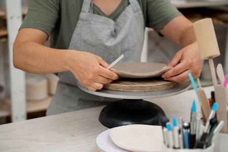 Using a sharp pottery carving knife to cut out a perfect round shape from clay. Ceramics class....