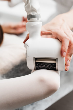 Lymphatic drainage procedure. Doctor is using lymphatic drainage to treat congestion in lymphatic system of the patient. Young woman is having a machine-guided lymphatic drainage procedureの写真素材
