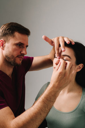Rhinoplasty. Applying bandage on nose after surgery to support its shape, decrease swelling and improve appearance. Plastic surgeon is taping nose to patient during rhinoplasty recoveryの写真素材