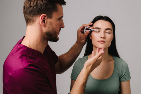 Upper blepharoplasty. Plastic surgeon is measuring surgical distance within eye of his patient using Castroviejo caliper. Preparing for blepharoplasty to correct droopy eye lidsの写真素材