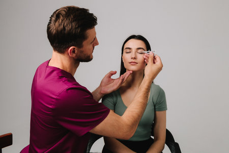 Preparing for blepharoplasty to correct droopy eye lids. Upper blepharoplasty. Plastic surgeon is measuring surgical distance within eye of his patient using Castroviejo caliperの写真素材