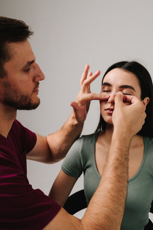 Rhinoplasty. Applying bandage on nose after surgery to support its shape, decrease swelling and improve appearance. Surgeon is taping nose to patient during rhinoplasty recoveryの写真素材