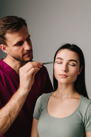 Upper blepharoplasty marking eyelid. Surgeon is checking distance in between dotted lines on eyelid with anatomical tweezersの写真素材