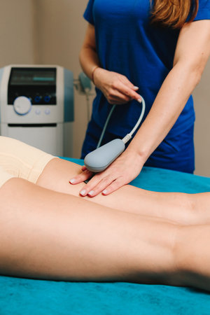 Young athlete is going through diathermy to heal from sports leg trauma. Effective pain management. Tecar therapy to help with post surgery rehabilitationの写真素材