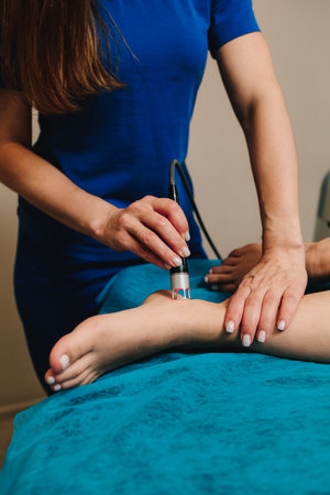 Woman is going through infrared procedure to relieve painful foot conditions, heal from injury and...