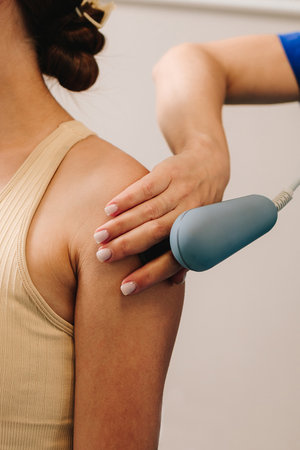 Diathermy. Doctor is doing tecar therapy to female patient to heal her injured shoulder. Using high...