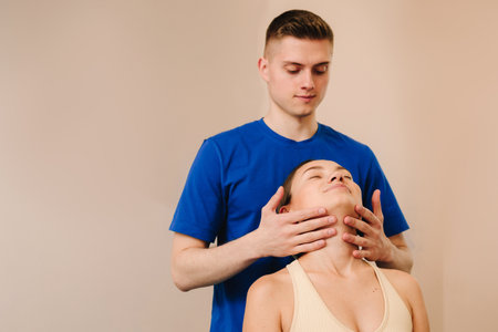Osteopath is stretching neck of female patient to reduce pain and reveal muscle tension. Doctor is detecting health issues by moving muscles of womanの写真素材