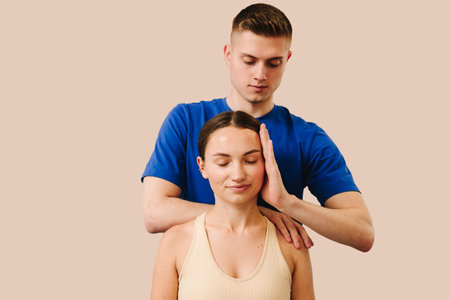 Doctor is detecting health issues by moving muscles of woman. Osteopath is stretching neck of female patient to reduce pain and reveal muscle tensionの写真素材