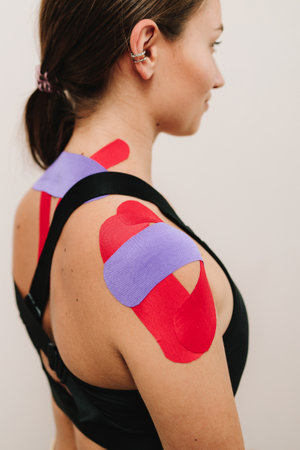 Medical tapes produce motion, improves posture and helps with stabilizing joints. Shoulder kinesiology taping creates muscle contraction to body of patientの写真素材