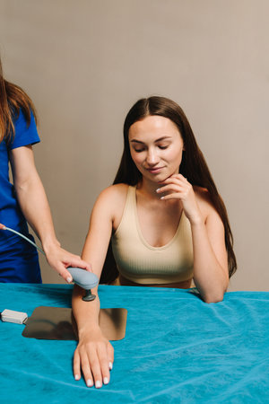 Diathermy. Young girl is healing from bruises and sprains on her arm. Effective use of tecar therapy...