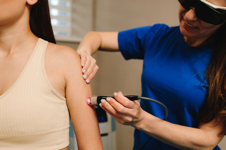 Arm laser therapy. Helping to relieve pain and inflammation with infrared light. Doctor wearing protective glasses is doing laser therapy on arm to patientの写真素材