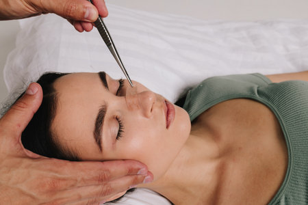 Post-surgery rhinoplasty care. Woman is having her nose taped after nose surgery. Preventing swelling, deforming and additional complications with special nose band aidの写真素材