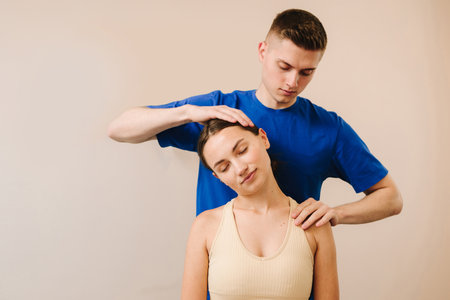 Osteopath is stretching neck of female patient to reduce pain and reveal muscle tension. Doctor is detecting health issues by moving muscles of womanの写真素材