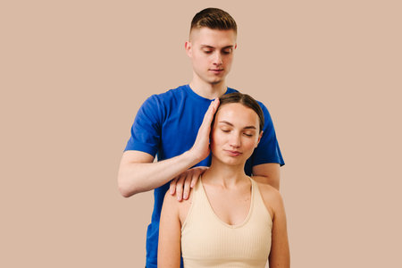 Doctor is detecting health issues by moving muscles of woman. Osteopath is stretching neck of female patient to reduce pain and reveal muscle tensionの写真素材