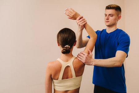 Doctor is doing osteopathy therapy to heal from back muscle conditions. Woman is having shoulder physiotherapy to reduce pain and increase range of motionsの写真素材