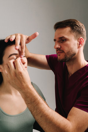 Rhinoplasty. Plastic surgeon is taping nose to patient during rhinoplasty recovery. Applying bandage on nose after surgery to support its shape, decrease swelling and improve appearanceの写真素材