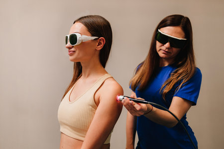 Laser therapy for chronic back pain. Woman is healing with red light to reduce pain, inflammation and edemas of her back. Effective laser therapy to restore damaged muscle tissues and nervesの写真素材