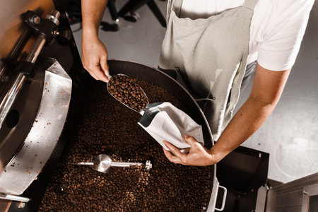 Pouring fried coffee grains in packaging bag in the facility. Packing roasted coffee beans into a craft bagの写真素材