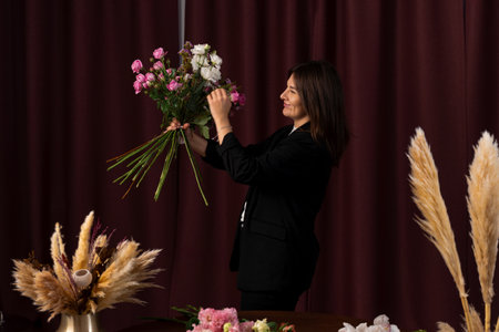 Florist woman is arranging a floral decoration, making bouquet for clients. Female florist is...