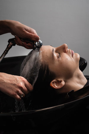 Hair wash in a beauty salon to get deeper cleaning. Hairdresser is washing hair to a female client before making a hairstyleの写真素材