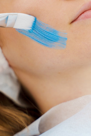 Getting facial treatment for a women with moisturizing mask by cosmetologist. Applying face mask for...