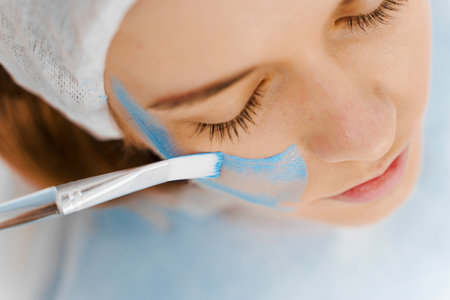 Getting face mask for a women in beauty center. Facial treatment with clay mask. Skincare wellness...