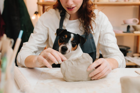 Potter with dog is making ceramic clay product on the table in the pottery workshop. Potter is sculpting wet clay for ceramics products.の写真素材