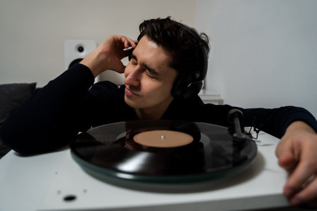 Cheerful hipster is listening to music by vintage vinyl records and feeling real emotions of music...