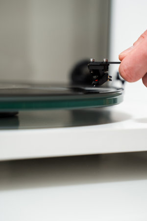 Musician adjusts tonearm on vinyl turntable. Music lover is holding tonearm in hand before playing the vinyl retro music on vinyl turntableの写真素材