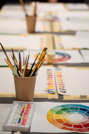 Art palette with watercolor paints and paintbrushes prepared for art masterclass. Organizing art...