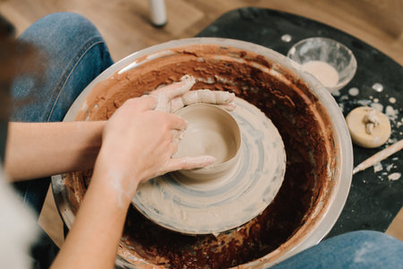 Artisan sculpts a pottery plate on the spinning wheel. Craftswoman is molding dish in the pottery studioの写真素材