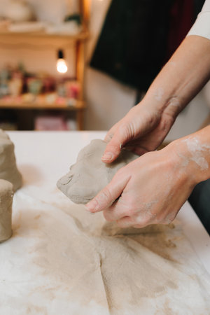 Potter is sculpting wet clay for ceramics products. Hands of a female potter making ceramic clay product on the table in the pottery workshopの写真素材
