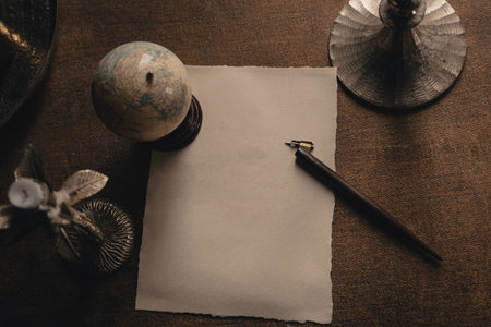 Old calligraphy ink pen are on the old-fashioned table. Ink pen and blank sheet on antique wooden...