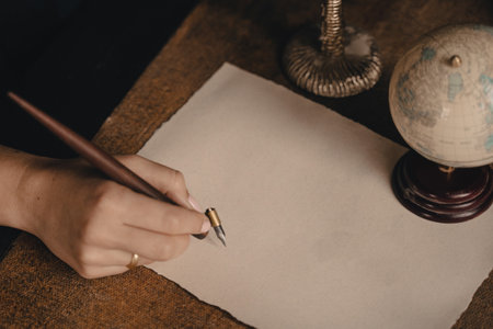 Ink pen writing on a blank piece of white paper. Calligraphic writing with a globe and a candlestick in an old-fashioned styleの写真素材