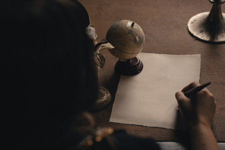 Ink pen writing on a blank piece of white paper. Calligraphic writing with a globe and a candlestick in an old-fashioned styleの写真素材