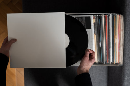 Vinyl music lover is selecting rock vinyl album from collection. Listen to music at home. Collection of vintage vinyl records at homeの写真素材