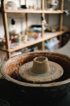 Potter sculpts a ceramic mug from clay in the pottery studio. Molding earthenware with potters toolsの写真素材