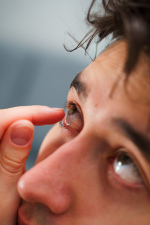 Correcting eye wellnesses with optical contact lenses. Man inserts a contact lens into eye for myopia treatmentの写真素材